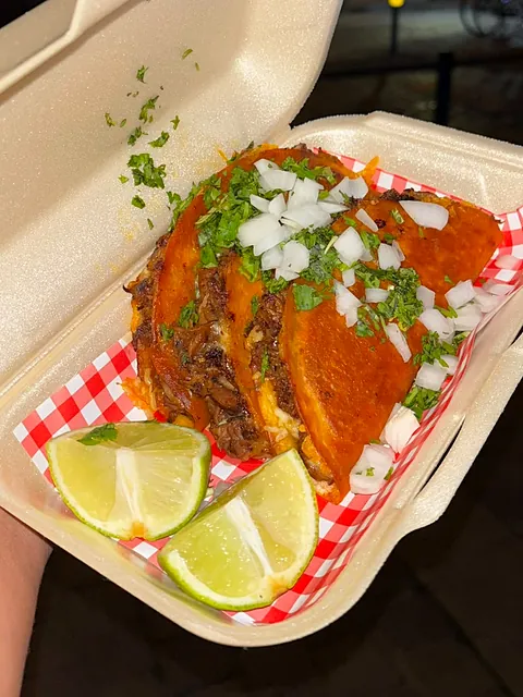 8h Birria Tacos met koriander, witte ui en limoen in een afhaaldoos op rood-wit papier